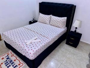 a bed with a black headboard and pillows at 2Bed Abidjan Apartment- Relax Explore & Unwind in Cocody