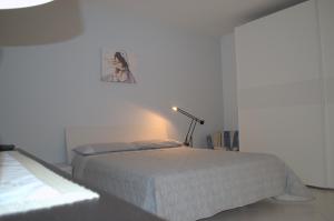 a white bedroom with a bed and a lamp at Casa Vacanze La Rocca in Matera