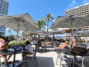 a group of people sitting at tables with umbrellas at Apartamento em Salinas Premium Resort in Salinópolis