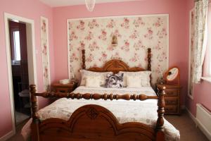 a bedroom with a large bed with pink walls at Ceecliff House in Culdaff