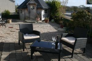 a patio with two chairs and a table and a house at Ceecliff House in Culdaff