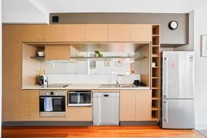 a kitchen with wooden cabinets and a white refrigerator at W30 - Sparkling North Melbourne Gem with parking in Melbourne