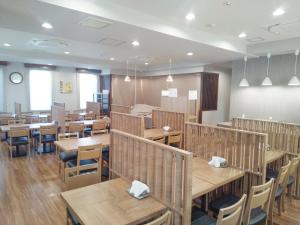 岐阜市にあるホテルルートイン岐阜県庁南の木製のテーブルと椅子が置かれた空のレストラン