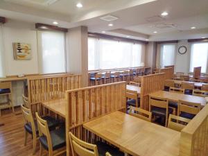 岐阜市にあるホテルルートイン岐阜県庁南の木製のテーブルと椅子が置かれた空のレストラン