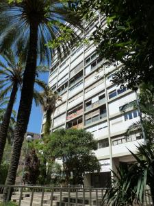 a tall white building with palm trees in front of it at Joanic Apartment Escorial in Barcelona