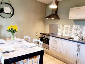 una cucina con tavolo e fiori gialli di Gîte au calme avec jardin, Wifi et parking près de Lille - FR-1-510-222 a Fournes-en-Weppes