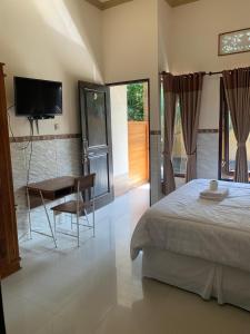 a bedroom with a bed and a desk and a television at Jepun Inn in Padangbai