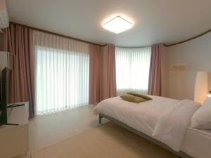 ソギポにあるSeogwipo Borisol Pensionのベッドと大きな窓のある寝室