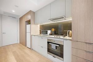 シドニーにあるCBD Center Gem Modern 1-Bedroom Aptの白いキャビネットと電子レンジを備えたキッチン