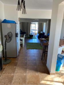 a kitchen with a refrigerator and a living room at Blumar El sokhna in Al Ḩafāʼir