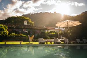 a pool with chairs and a table and an umbrella at Yes Please! Hostel in Antigua Guatemala