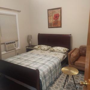 a bedroom with a bed and a couch and a chair at Deluxe Room E in Jersey City