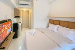 RawalembangRelaxing and Cozy Studio Tokyo Riverside PIK 2 Apartment By Travelio的一间配有床和电视的酒店房间