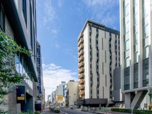 a tall building on a city street with buildings at Hotel Vista Nagoya Nishiki in Nagoya