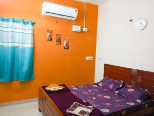 a bedroom with a bed and an orange wall at Jas Homestay Madurai in Tirupparangunram