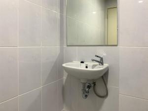 a white bathroom with a sink and a mirror at Comfortable and Spacious 1BR Tokyo Riverside PIK 2 Apartment By Travelio in Rawalembang +8 photos