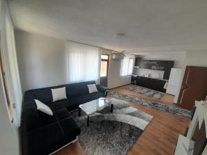 a living room with a black couch and a kitchen at Levkov in Petrich