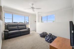 a living room with a couch and a flat screen tv at Noojee 27 Ballina Crescent in Port Macquarie