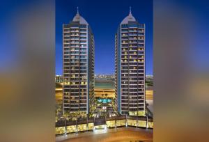 two tall buildings in a city at night at Atana Hotel in Dubai