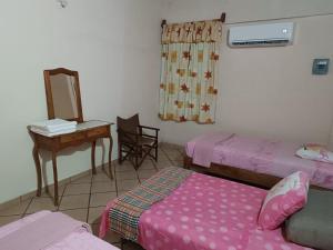 Cette chambre comprend deux lits, un bureau et un miroir. dans l'établissement La Casa Bonita, à Agua de Correa