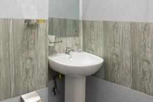 a white sink in a bathroom with green and gray wallpaper at Lakru Home Stay in Weligama