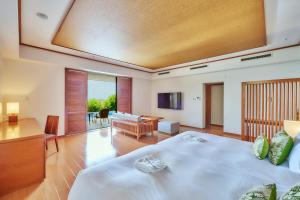 a bedroom with a large bed and a living room at Miyakojima Kurima Resort Seawood Hotel in Miyako-jima