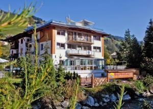 ein Haus auf einem Hügel neben einem Fluss in der Unterkunft Hotel Sonnberg in Saalbach-Hinterglemm