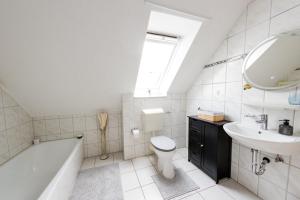 La salle de bains est pourvue de toilettes, d'un lavabo et d'une baignoire. dans l'établissement Großzügiges Wohlfühlhaus zwischen Stadt & Meer, à Hinte 40 autres photos