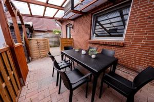 une table et des chaises noires sur une terrasse avec une fenêtre dans l'établissement Großzügiges Wohlfühlhaus zwischen Stadt & Meer, à Hinte