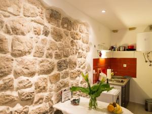 una cocina con una pared de piedra y una mesa con una planta en Apartment Lee Loo - Studio Apartment, en Dubrovnik