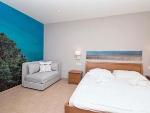 um quarto com uma cama e uma cadeira em Apartments Antonio - Studio with Balcony 2 1 - 5 em Tučepi