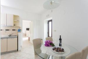 a white kitchen with a glass table with a bottle of wine at Apartments Maria Kolo ep - Two Bedroom Apartment with Terrace and Garden View in Koločep