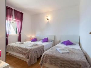 two beds in a room with purple pillows at Apartments Nena ST - One Bedroom Apartment with Terrace and Sea View A4 in Pisak