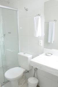 a white bathroom with a toilet and a shower at Sul América Palace Hotel in Belo Horizonte