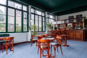 a restaurant with wooden tables and chairs and windows at Hôtel Restaurant Du Château in Josselin