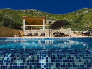 ein Swimmingpool mit Stühlen und einem Sonnenschirm in der Unterkunft Villa Dundo Pero - Four Bedroom Villa with Swimming Pool and Sea View in Babino Polje