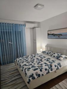 a bedroom with a bed with a blue and white comforter at AS Apartment in Podgorica