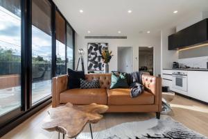 a living room with a brown couch and a kitchen at Trendy New York-Style Condo in Vibrant St Kilda in Melbourne
