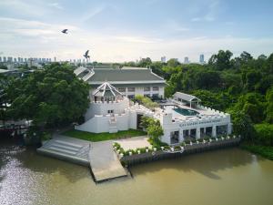 暖武里府Kalanan Riverside Resort的水面上白色大房子的空中景色
