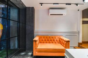 an orange leather couch sitting in a room at FabHotel Sivalika Inn - Howrah in Kolkata