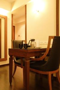 a wooden table with two chairs and a tea kettle on it at Hotel Amigo in Mumbai