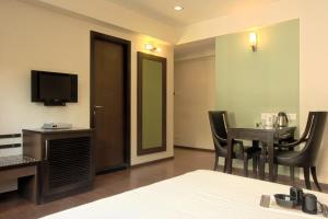 a hotel room with a bed and a table and a television at Hotel Amigo in Mumbai