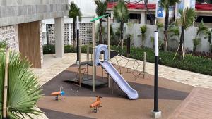 a playground with a slide in a courtyard at Homey and Cozy Designed 2BR at Tokyo Riverside PIK 2 Apartment By Travelio in Rawalembang