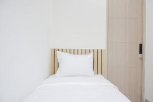 a bed with a white pillow in a room at Homey and Cozy Designed 2BR at Tokyo Riverside PIK 2 Apartment By Travelio in Rawalembang +27 photos