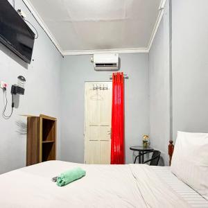 a bedroom with a bed and a red curtain at Q-Five Guest House YIA Kulon Progo Mitra RedDoorz in Temon