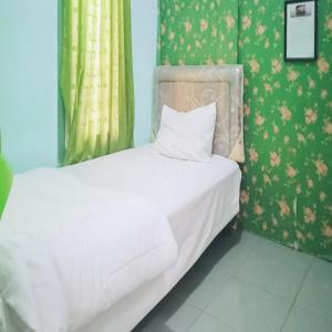 カラワンにあるAcintyya Homestay Syariah RedPartnerの緑の壁の小さなベッドルーム(白いベッド1台付)