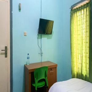 カラワンにあるAcintyya Homestay Syariah RedPartnerのベッドルーム1室(ベッド1台、デスク、緑の椅子付)