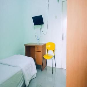 カラワンにあるAcintyya Homestay Syariah RedPartnerのベッドルーム1室(ベッド1台、デスク、黄色い椅子付)