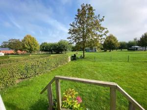 a wooden fence in a green field with a tree at Gastenverblijf op rustige camping in Zeeland in Kats