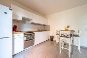 eine Küche mit weißen Schränken, einem Tisch und einem Kühlschrank in der Unterkunft Superbe appartement 1min métro7 Rez-de-chaussée in Aubervilliers